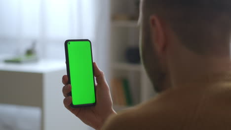 guy-is-looking-on-green-screen-of-smartphone-holding-vertically--modern-gadget-and-app-for-education-communication-and-entertainment-closeup-view